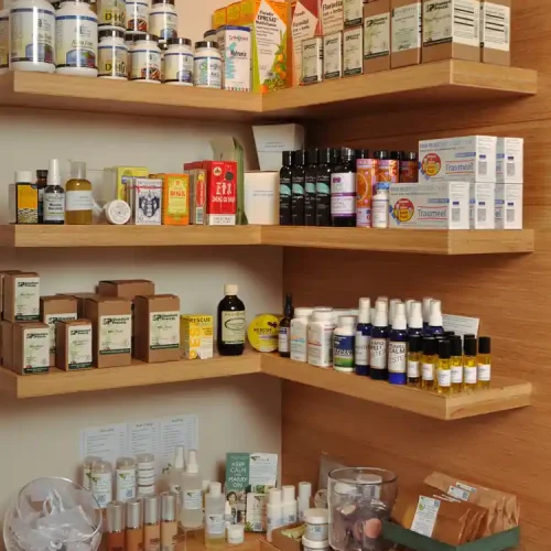 Wooden shelves displaying various health and wellness products, including bottles, boxes, oils, and herbal remedies.